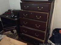 Front view of the Bassett tall bureau showing five drawers with brass pulls and keyholes. Dark brown finish, classic style.