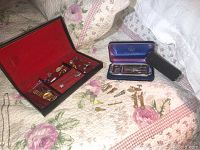 Wide shot showing vintage Rolls Razor in original case, men's tie tacks, cuff links, pins, and additional jewelry on floral quilted surface.
