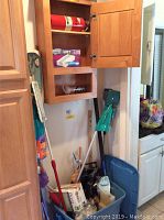 Cleaning supplies, fire extinguisher, and mop heads in wooden cabinets and plastic tub