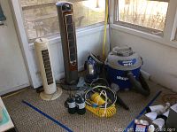Two vertical fans, Shop Vac vacuum, Bissell cleaner, cables and propane tanks, showing overall contents of lot.