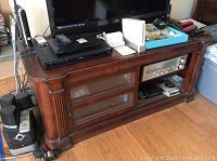 Photo of TV stand holding Sony BluRay player, vintage Technics receiver, Nintendo Wii console and games case, remote controls, and other small electronics.