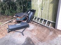Wide view showing all items together including wheelbarrow, ladders, PreciseFit lawn sweeper, tarp and grass catcher bag