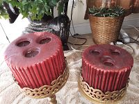 Two red pillar candle holders on gold metal stands, showing the top with three holes on each candle holder.