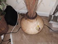 Top-down view of large round ceramic vase on floor with painted designs