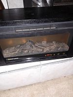 Heat Surge electric fireplace insert powered off, showing log arrangement inside the fireplace display.