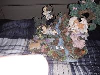 Overall view of musical angel figurine display with a waterfall, cherubs, deer, tree, and swans on a plaid fabric background.