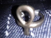 Close-up of the peace and love ring in a twisted metal style on a dark fabric background.