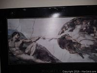 Framed picture of Michelangelo's The Creation of Adam showing the scene of God and Adam nearly touching hands.