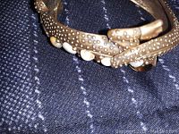 Close-up photo of part of the copper lizard bracelet showing textured body and white bead accents.