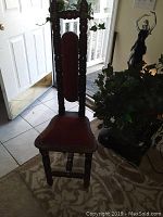 Front view of the antique-style red velvet chair with tall ornate wooden backrest and padded seat.