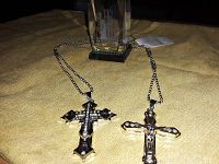 Clear crystal block with etched image of New York Twin Towers and two silver-tone cross necklaces with decorative stones on a yellow cloth.