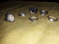 Photo of six ladies rings on yellow fabric background, showing all designs and stone details clearly