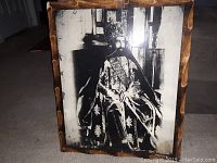 Front view of the old black and white photograph showing a seated royal figure in ornate ceremonial dress and crown, held in a rustic wooden frame.