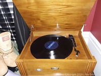 Front view of the record player inside its wooden cabinet playing a vinyl record.