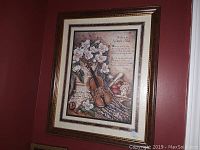 Framed picture on wall depicting a violin with flowers and a poem.