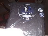 Dark gray Dallas Mavericks team shirt featuring team logo and '1980' on front, folded and tagged.