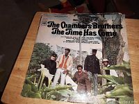 Photo of The Chambers Brothers vinyl record cover with title 'The Time Has Come' showing band members standing outdoors by a tree and plants.