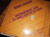 Front cover photo of Donna Summer vinyl record "Unconditional Love" and "She Works Hard For The Money" remixed dance club versions, limited edition, showing slight wear.