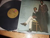 Vinyl LP record and album cover showing two men, one seated and one standing, with lyrics or credits on the album back cover