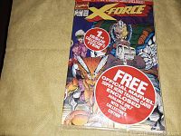 Photo of front cover of X-Force Issue #1 comic book showing comic characters, with large red sticker noting Issue #1 collector's item and free official Marvel trading card enclosed for collector's edition.