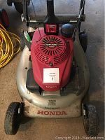 Front view of the Honda lawn mower showing red engine cover labeled Easy Start, Honda and Twin Blade 3-in-1 System on metal body.