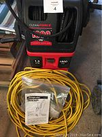 Front side of Clean Force 1800 PSI power washer with yellow power cord and paperwork on floor