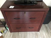Front view of the two-drawer lateral file cabinet with locked top drawer and keys inserted in lock.
