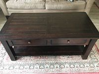 Full top-down view of the dark wood coffee table placed on a patterned rug in front of a beige couch.