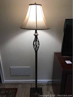 Full view of lit floor lamp showing height, base, and shade in context of room.