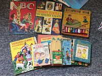 Photo displaying an assortment of vintage children's books with colorful covers and a book with a small wooden xylophone attached.