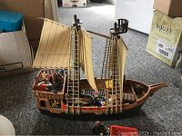 Side view of vintage Playmobil pirate ship showing detailed hull, two sails, rigging, and mounted figurines onboard.