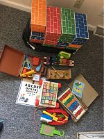 Set of multi-colored cardboard building blocks with brick patterns along with various vintage toys including wooden xylophone and ABC blocks on the floor.