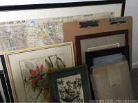 Group photo showing six framed artworks leaning against a wall, including a large detailed map and floral prints.