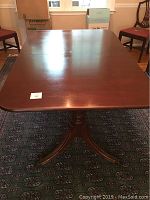 Top view of rectangular wooden dining table with glossy finish and visible center line for leaf insert.