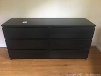 Front view of dark finish Ikea dresser showing six drawers in two columns of three.