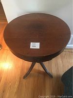 Top view of a round wooden table with scratches and wear on the surface, showing the overall size and finish.