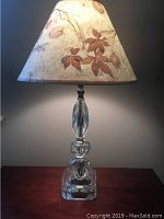 Glass antique table lamp with clear faceted glass base and tapering glass column, lit to show form