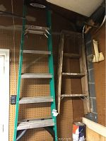 Photo showing the 6 ft Werner ladder alongside the 4 ft wooden ladder mounted on a garage wall.