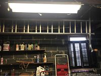 Side view of aluminum extension ladder hanging horizontally above garage shelves containing various liquid containers and automotive supplies.