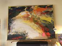 Front view of the large signed abstract painting with metal brass-like frame on wall