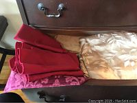 Drawer with folded red and pink patterned linens, beige leafy linen