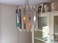 Full view of the hanging lamp suspended from chain, showing alternating metal and plastic vertical panels forming a cylindrical shade.