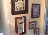 Photo showing five assorted framed wall art pieces hung on a wall including family-themed print, abstract mirror, small photo frame, and two decorative prints.