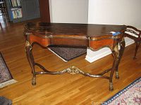 Full view of the wooden hall console table showing scalloped top edge, carved legs, and gold accents.