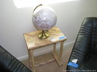 End table with faux marble top and carved legs with globe on top, showing overall condition and design.