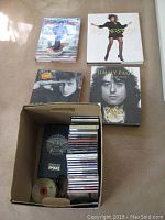 Overall view of four Rolling Stone hardcover books on floor beside a box containing multiple compact discs and jewel cases