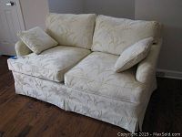 Front view of Frederick Edward loveseat showing cream fabric with beige floral pattern and two throw pillows