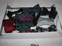 Eleven assorted silk bow ties arranged in a box, multiple designs and colors visible