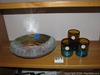Glass bowl with patina gold finish measuring 12 inches and three Mexican votive candle holders arranged on wooden shelf.