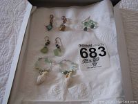 Four pairs of costume jewelry earrings displayed on a white cloth with MaxSold lot number 683.